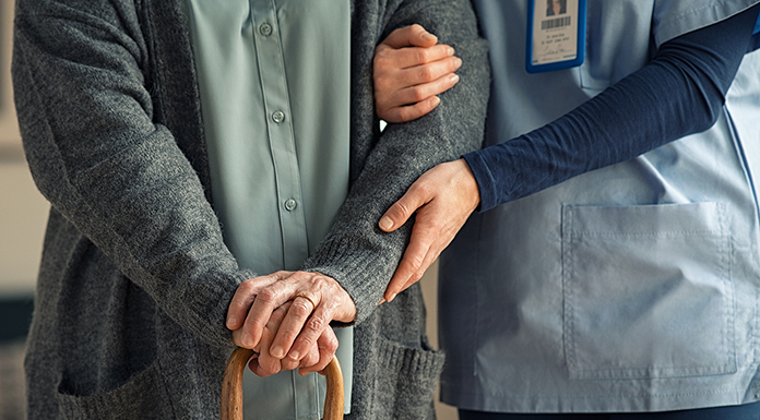 Close up hands of caregiver doctor helping old woman at clinic