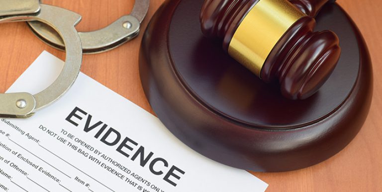 A gavel, handcuffs and legal paperwork on a desk.